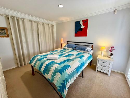 a bedroom with a bed with a blue and white comforter at Beachside Escape - Broadwater in Broadwater
