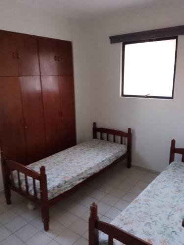a bedroom with two beds and a window at Apartamento com piscina e churrasqueira privativas in Cabedelo