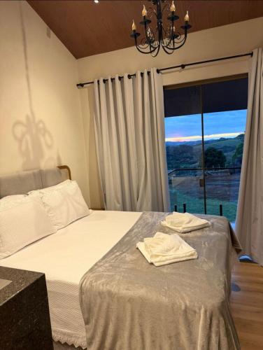 a bedroom with a bed and a large window at Pousada Refúgio Pietra Blu in Domingos Martins