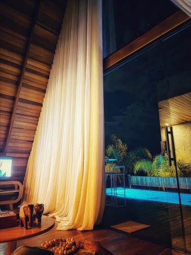 a living room with a curtain next to a pool at Zamaya Bangalôs in Sao Jorge