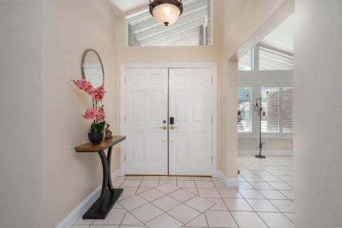 a hallway with a white door and a table with flowers at Your Poolside Hideaway in Bakersfield