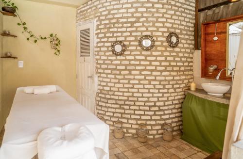 a bathroom with a brick wall with a bed and a sink at Espaço Fateixa in Jericoacoara