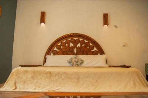 a bed with a wooden headboard in a bedroom at Casa X'Lapac in Valladolid