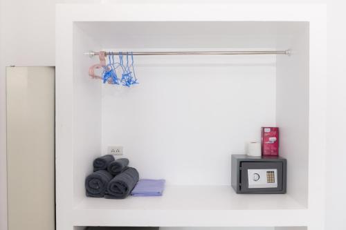 a white wall with a shelf with towels and a clock at IBIZA BEACH Resort in Haad Yao