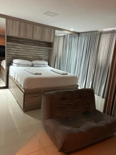 a bedroom with a large bed and a chair at Lounge 22 barato 12e13agosto in Goiânia