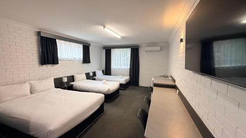 a hotel room with two beds and a flat screen tv at Blue Violet Motor Inn in Toowoomba