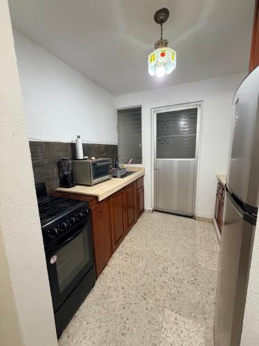 a kitchen with a stove and a refrigerator at Cómodo departamento en planta baja con dos recámaras in Villahermosa