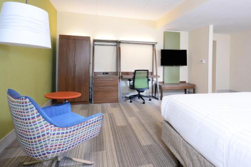 a hotel room with a bed and a chair and a desk at Holiday Inn Express & Suites Raleigh Durham Airport at RTP by IHG in Durham