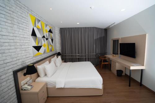 a bedroom with a bed and a desk and a television at Nite & Day Laguna Bintan in Tanjung Pinang