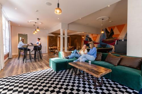 a woman sitting on a couch in a living room at Haka House Christchurch in Christchurch