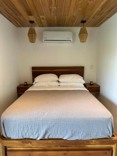 a bedroom with a large bed with two pillows at Ruca Lodge - Luxury Container Tiny Home Surrounded by Nature in Uvita