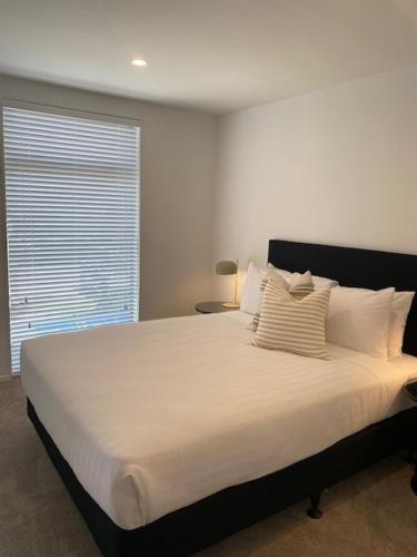 a bedroom with a large white bed with a window at Colombo Executive Apartments in Christchurch
