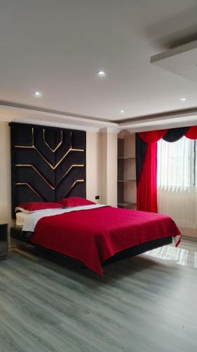 a bedroom with a large bed with a red blanket at Hostal Imperio la Kennedy in Quito