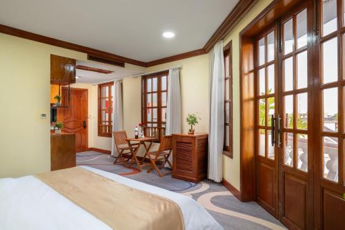 a bedroom with a bed and a table and windows at Domi Hotel in Siem Reap