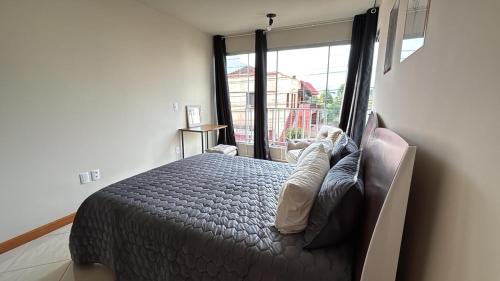 a bedroom with a bed and a large window at Apartamento no Centro 2 Wi-Fi Garagem in Vacaria