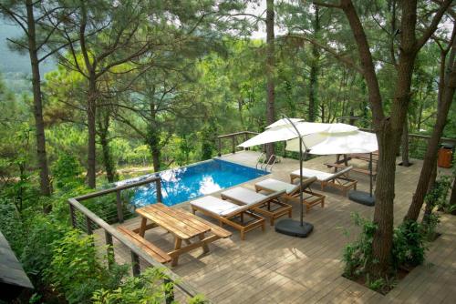 a deck with a pool and tables and an umbrella at Amaya Retreat in Sóc Sơn