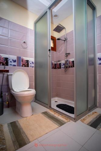 a pink bathroom with a toilet and a shower at Cabral residence in Guediawaye