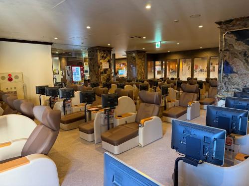 a salon with a waiting room with chairs and televisions at Capsule Hotel Sauna G -topia male Only in Funabashi