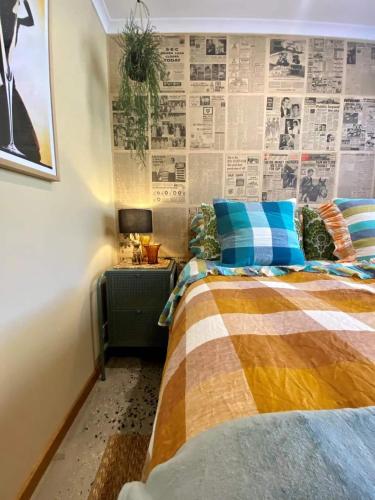 a bedroom with a bed and a wall covered in newspapers at Lydiard General Cafe Delight in Ballarat