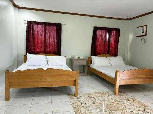two beds in a bedroom with red curtains at Pableo's Pension House in Moalboal in Moalboal
