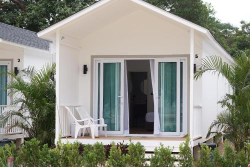 a white house with a white chair on a porch at Travellers Palm in Ko Phangan