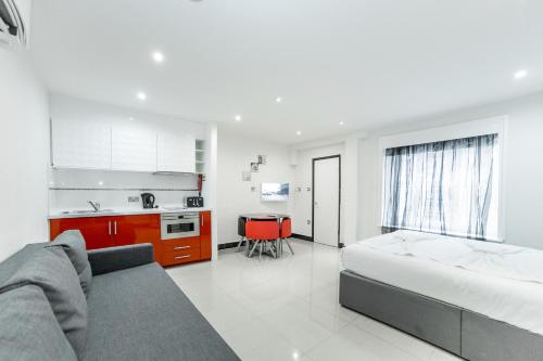 a white bedroom with a bed and a kitchen at Imperial Court Suites in London