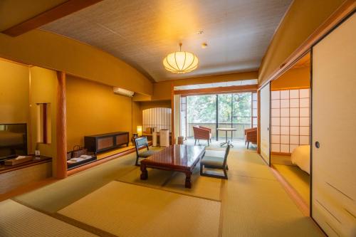 ein Wohnzimmer mit einem Holztisch und Stühlen in der Unterkunft 源泉の湯 福の屋 in Minakami