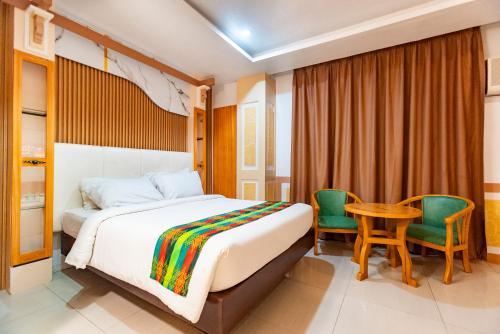a bedroom with a bed and a table and chairs at LM METRO HOTEL in Zamboanga