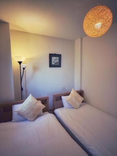 two beds in a room with a lamp and a chandelier at Uhome Ueno Hotel in Tokyo