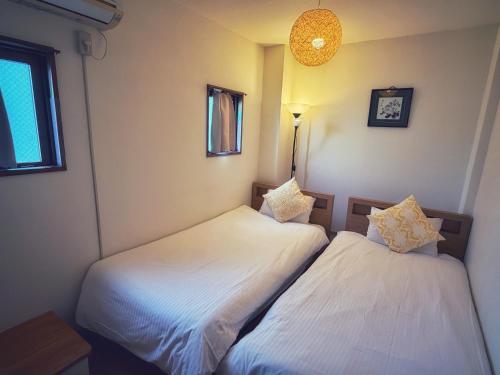 two beds in a room with white sheets at Uhome Ueno Hotel in Tokyo