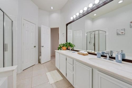 a white bathroom with two sinks and a large mirror at 4BD Cozy Frisco Fun Stay! in Frisco