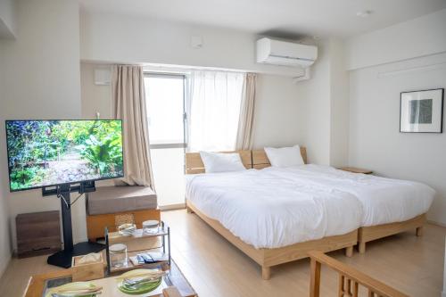 a bedroom with a large bed and a flat screen tv at Hotel HIRAKU RYUKYU -STYLE- in Naha