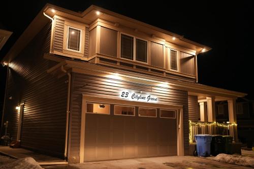 a house lit up at night with a garage at Cozzy Cityscape & Airport Retreat in Calgary