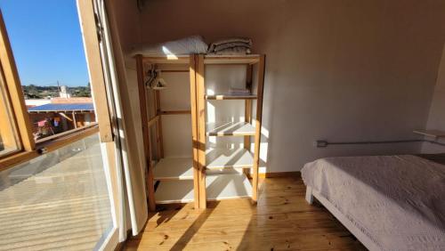 a room with a bed and a book shelf next to a window at Casa Lavion in Colonia Chapadmalal