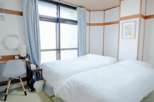 a bedroom with two beds and a window at 高松の宿晴れとケ in Takamatsu