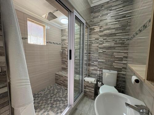 a bathroom with a shower and a toilet and a sink at The Marley in Polokwane