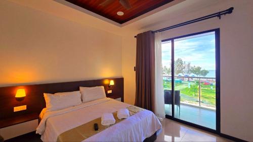 a bedroom with a bed and a large window at Badungun Seaside View in Kuala Penyu