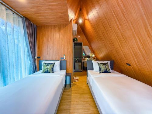 two beds in a room with wooden walls and wooden floors at The View A-Frame Cabin in Chiang Dao