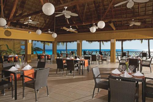 a restaurant on the beach with tables and chairs at Secrets Aura Cozumel - Adults Only in Cozumel