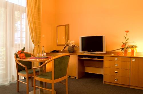 a desk with a television and a table with chairs at Penzion Franko in Zvolen