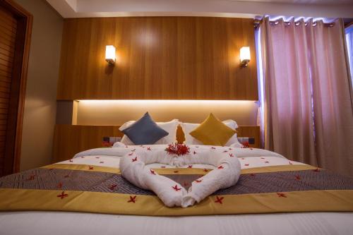 a bedroom with a bed with a towel animal on it at Kuredhi Beach Inn in Maafushi