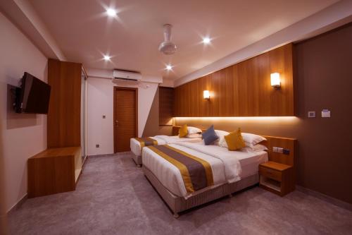 Habitación de hotel con 2 camas y TV de pantalla plana. en Kuredhi Beach Inn, en Maafushi