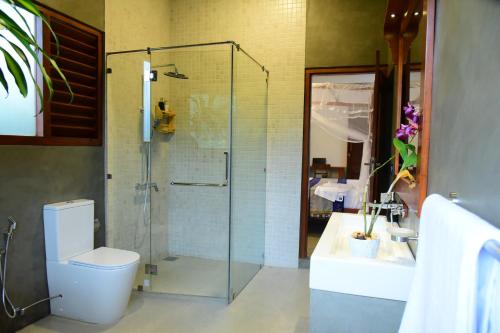 a bathroom with a toilet and a glass shower at Moon Lanka Hotel Hikkaduwa in Hikkaduwa