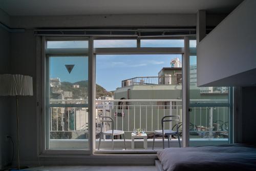 a bedroom with a balcony with a view of the city at Casa Blanca Guesthouse in Nagasaki