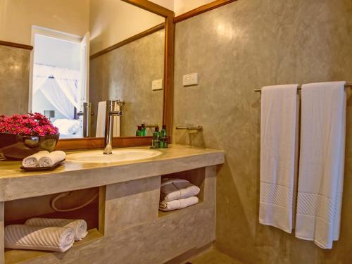 a bathroom with a sink and a mirror and towels at The Lagoon Villa in Negombo