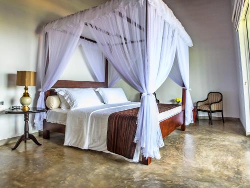 a bedroom with a canopy bed and a table at The Lagoon Villa in Negombo