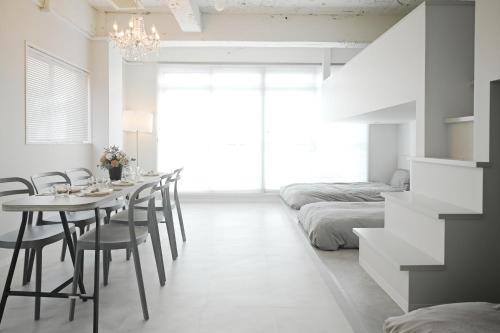 a dining room with a table and chairs and a bed at Casa Blanca Guesthouse in Nagasaki