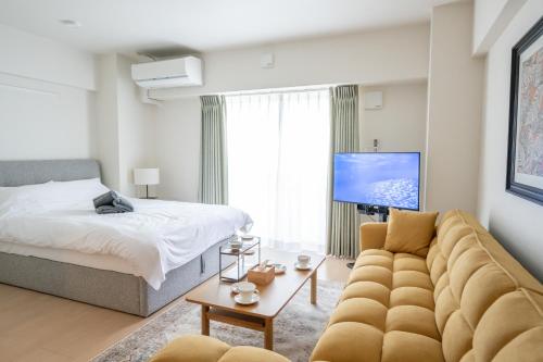 a living room with a couch and a bed at Hotel HIRAKU RYUKYU -STYLE- in Naha
