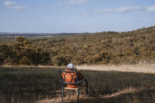 a person sitting in a chair in a field at Tallarook Hilltop Tiny House 1 by Tiny Away in Tallarook