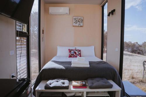 a small bedroom with a bed and a large window at Tallarook Hilltop Tiny House 1 by Tiny Away in Tallarook